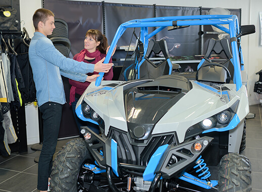 People inspecting a blue dune buggy in Monster Experience showroom