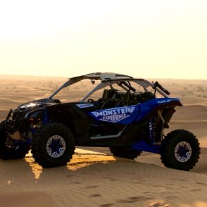 Side view of blue Monster Experience Dune buggy parked on a sand dune in the Dubai Desert at sunrise