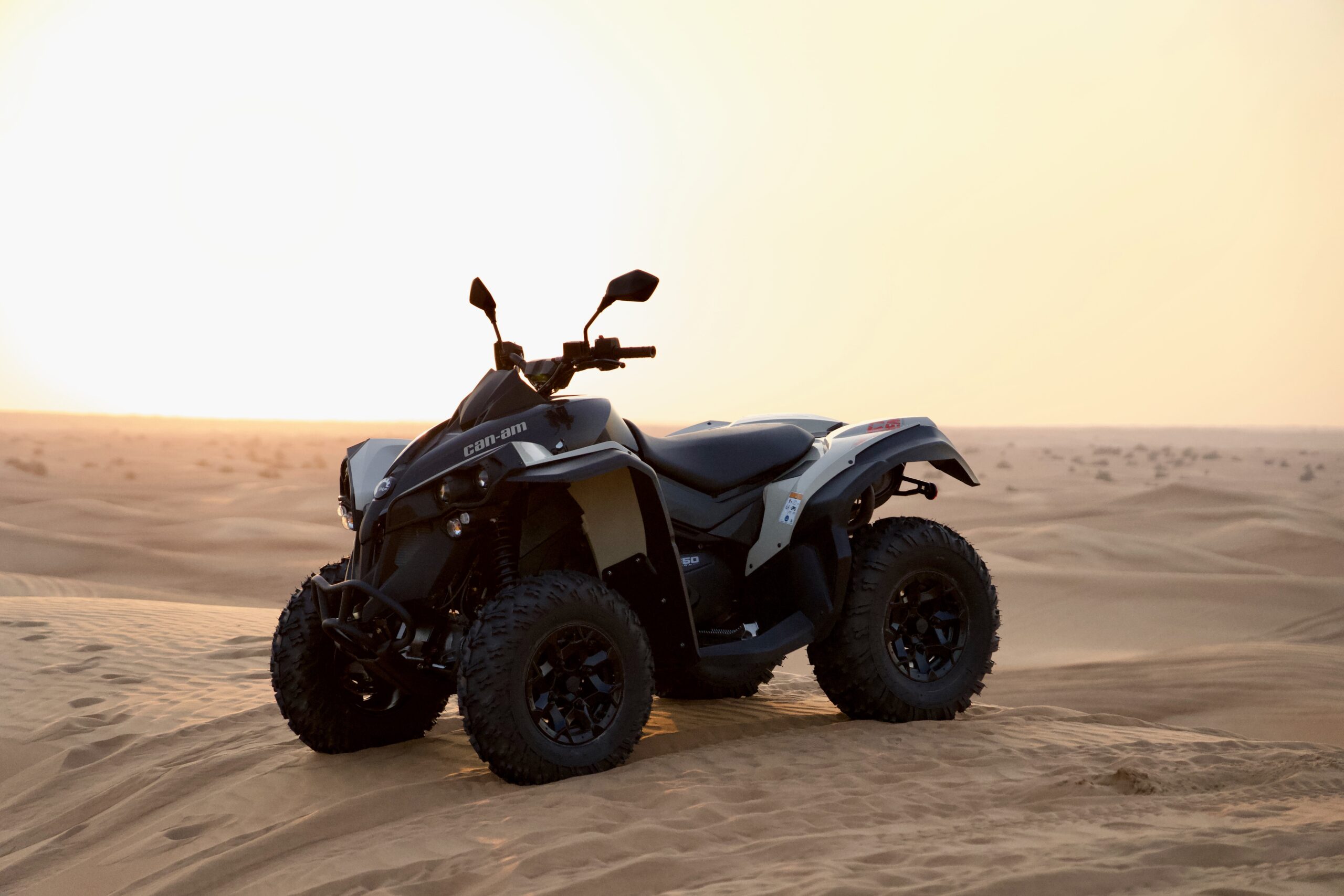Monster Experience Can Am Quad Bike parked on a sand dune in the Dubai Desert at sunset
