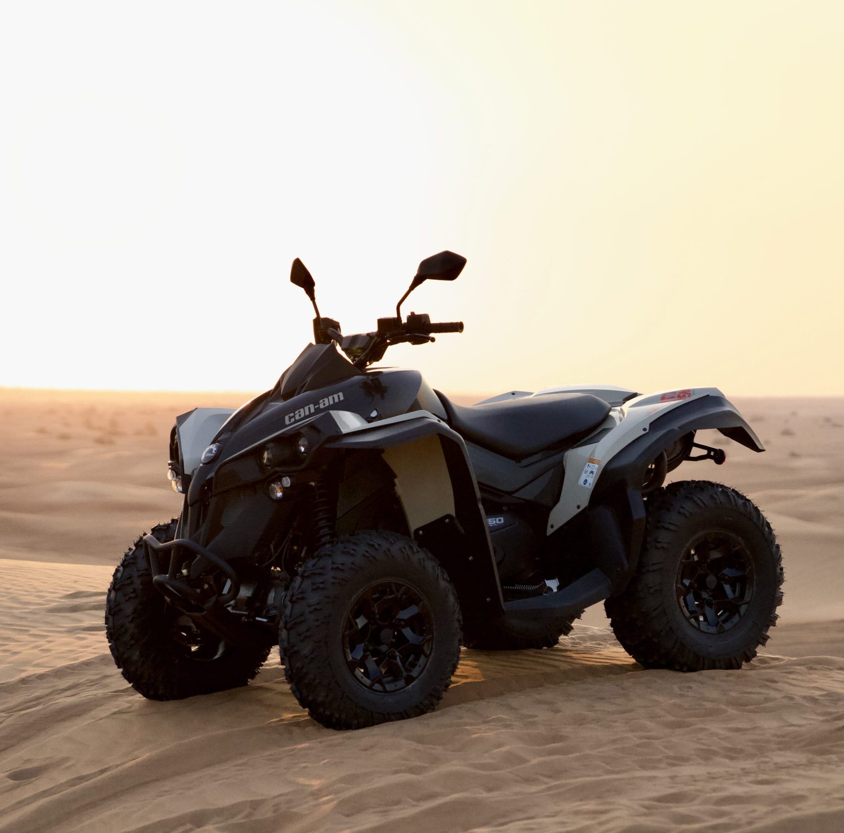 Monster Experience Can Am Renegade 650CC quad bike parked on a sand dune in the Dubai Desert at sunset