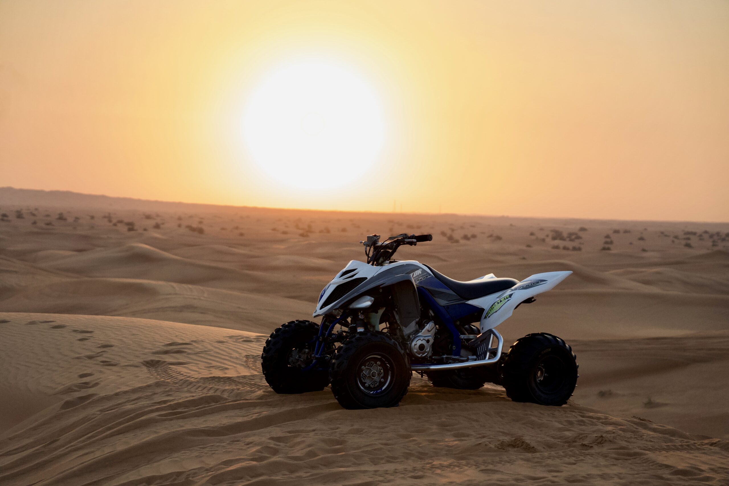 YAMAHA RAPTOR 700CC parked on a sand dune in the Dubai Desert at sunset during a quad biking tour