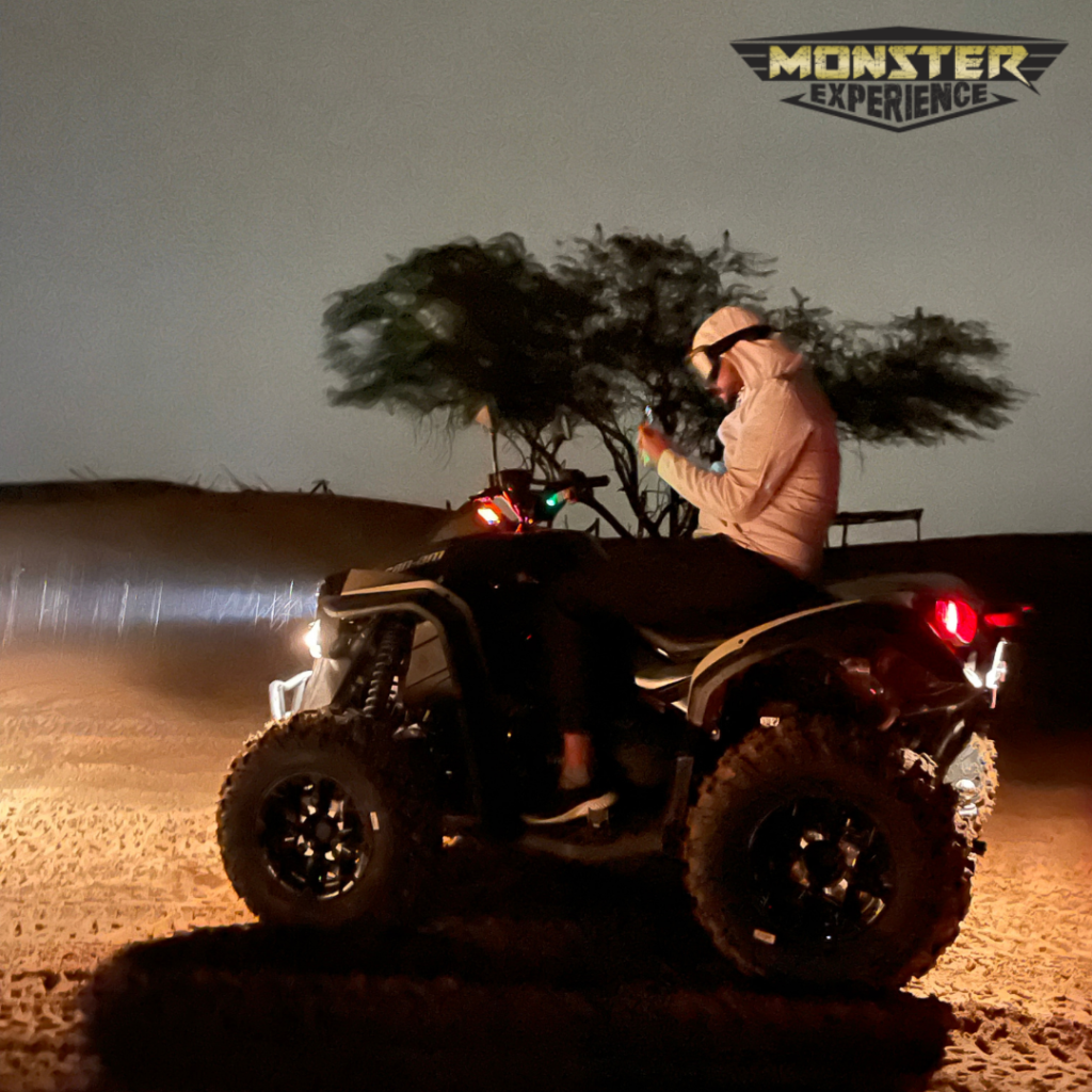 Man sitting on Monster Experience branded Quad Bike In Dubai Desert at night