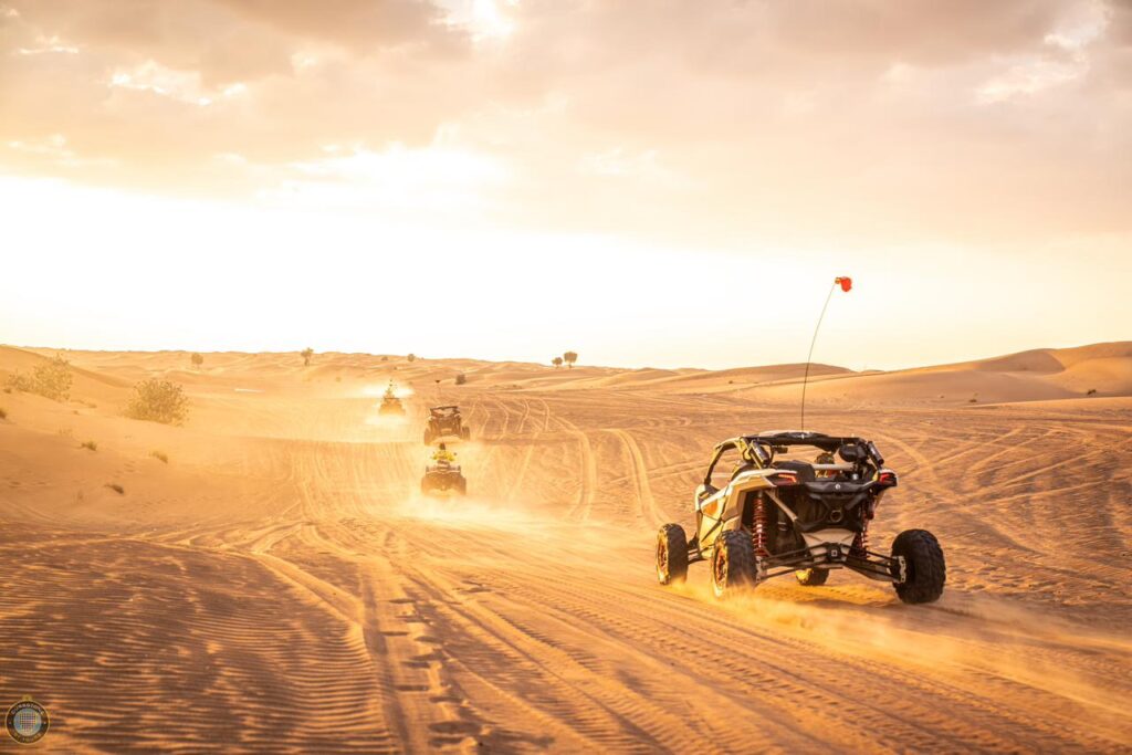 Monster Experience dune bashing in the Dubai desert with bright sun and dust clouds