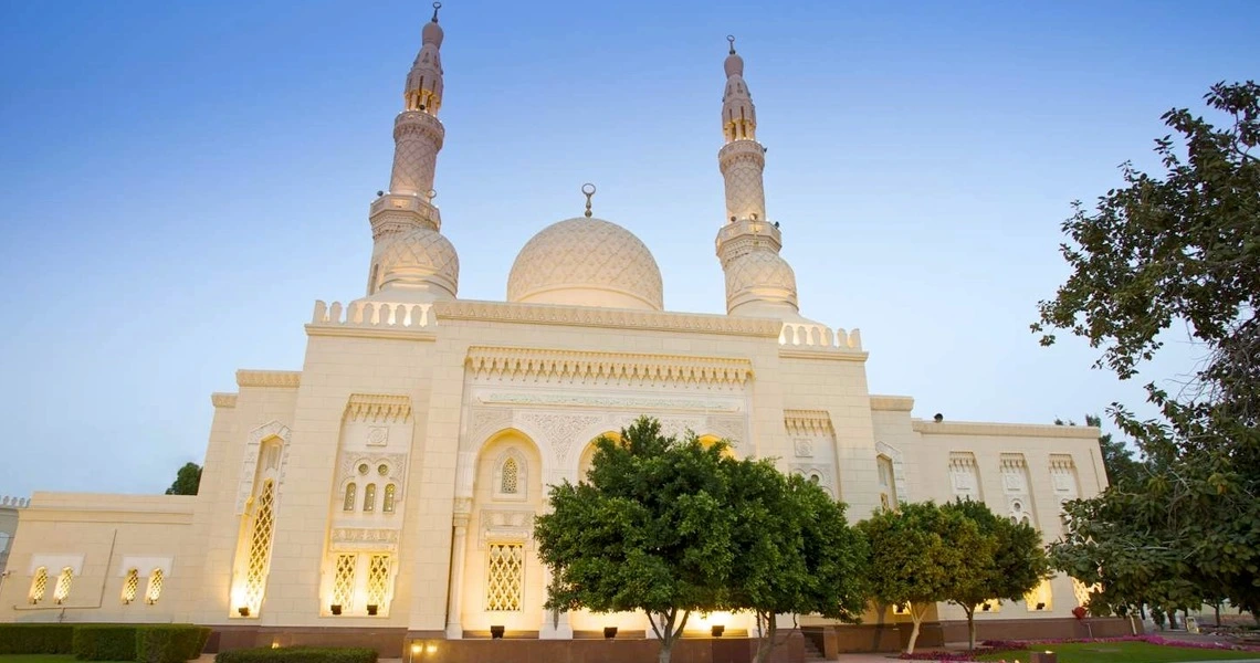 Jumeirah Mosque - a white beautiful mosque with 2 towers and 1 dome in the middle - cream color with some trees around