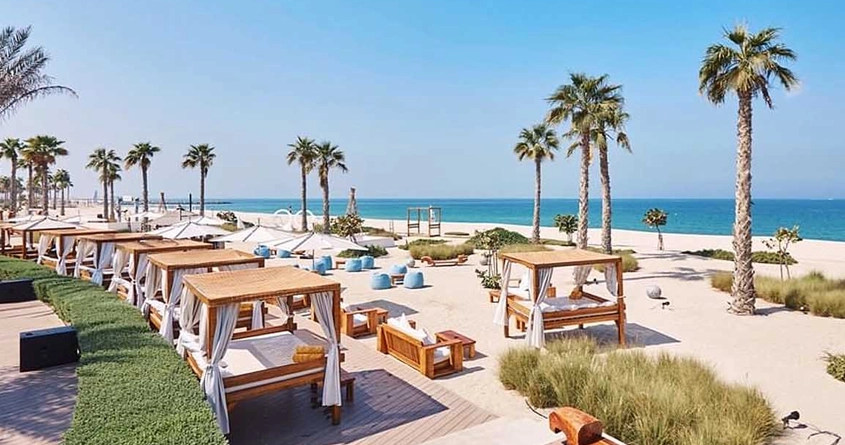Nikki beach Dubai - a beach with palm trees and chairs