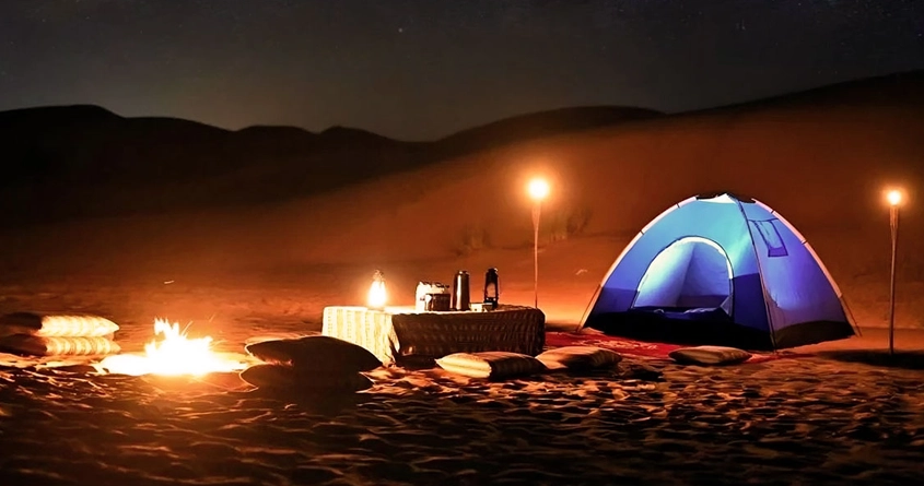 night desert safari camping with blue beautiful tent and lamps around at night in the desert