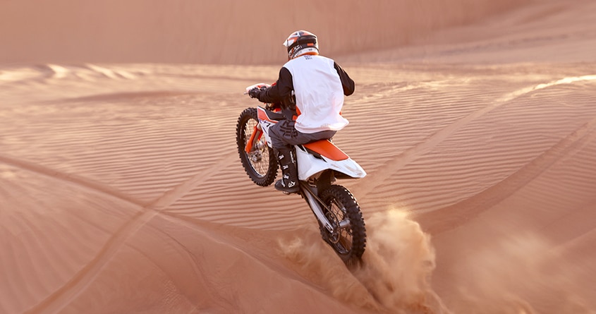 Off road biking - a rider dirt biking in desert dunes