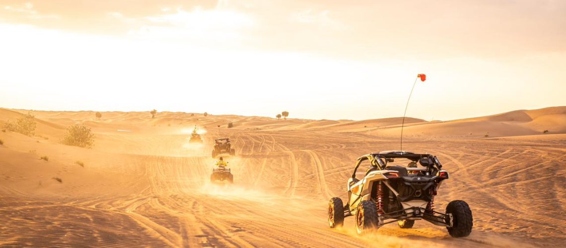 Monster Experience dune bashing in the Dubai desert with bright sun and dust clouds